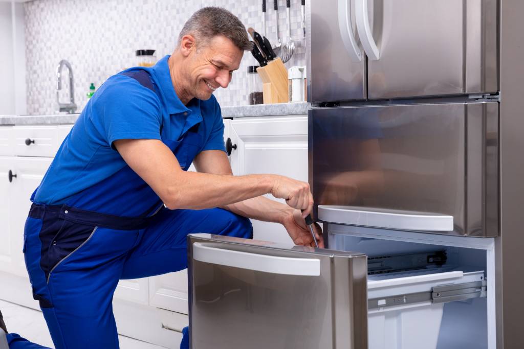 Smiling technician repairing a refrigerator